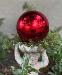 A red ball on a statue
Description automatically generated